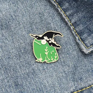 Close-up of a cute green witch frog enamel pin on a blue denim jacket collar