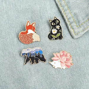 Cartoon enamel animal pins with fox, cat and bear designs on blue denim fabric