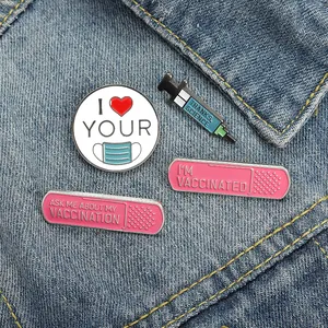 Set of four vaccine-themed enamel pins featuring heart masks and syringes on denim