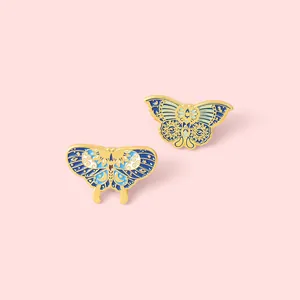 Detailed close-up of blue celestial butterfly enamel pins with sun and moon patterns