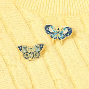 Detailed macro of two blue butterfly enamel pins with celestial motifs on yellow knit