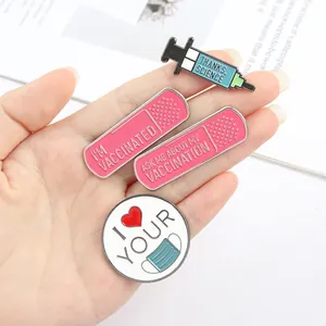 Detail view of set of four medical-themed enamel pins held in hand for scale and texture