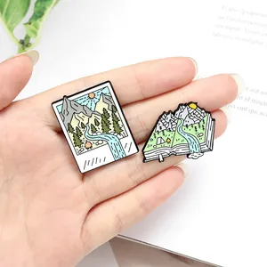 Detailed macro view of creative nature-themed enamel pins featuring mountains and rivers