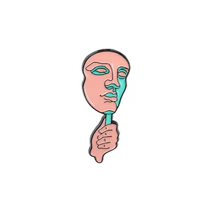 Detailansicht der Emaille-Gesichtsmasken-Brosche mit Hand, die grüne Maske hält