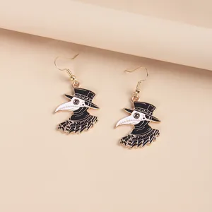 Detail of creative plague doctor earrings featuring a bird mask and cross on gold hooks