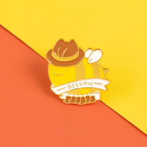 Detail of cute enamel bee badge wearing cowboy hat and boots with BEEHAW text