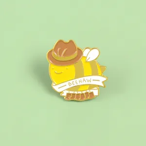 Detail of cartoon bee enamel pin with cowboy hat and Beehaw banner text