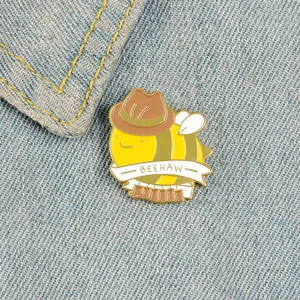 Macro shot of cartoon bee enamel pin with Beehaw banner on blue denim fabric background