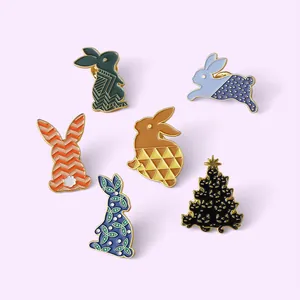 Lot détaillé de six broches émaillées avec divers lapins et un sapin sur fond violet