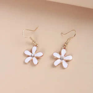 Close-up of golden daisy earrings with white enamel petals and small zircon centers