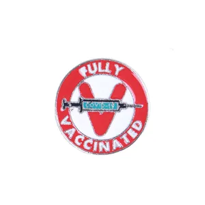 Macro detail of alloy enamel pin with Fully Vaccinated text and COVID-19 syringe design