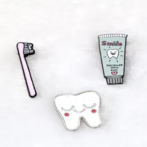Cartoon tooth and toothpaste enamel pins set on a soft white plush background