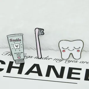 Detailed view of three enamel badges featuring a mint toothpaste, pink toothbrush, and tooth