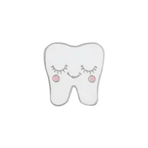Detailed close-up of a cute white tooth enamel pin with a smiling cartoon face and silver trim