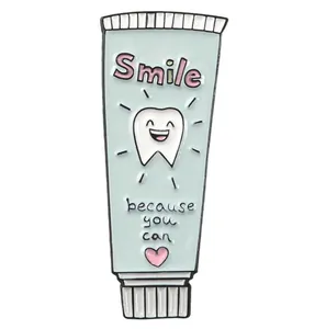 Detail of toothpaste enamel pin with Smile text and cute cartoon tooth on blue surface