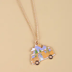 Close-up of golden necklace with colorful enamel camper van and mountain pendant