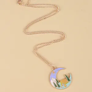 Macro detail of crescent moon pendant necklace with painted forest and mountain scenery