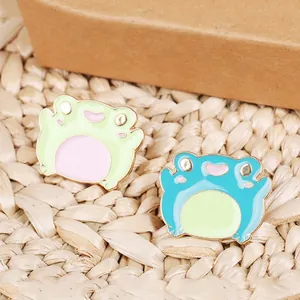 Set of two cute cartoon frog enamel pins in pastel green and blue-green colors