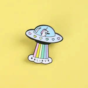 Detail der Emaille-Einhorn-UFO-Brosche mit Regenbogenstrahl und Believe-Text auf Gelb
