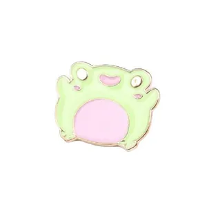 Detailed view of a cute light green cartoon frog enamel pin with gold metal outlines