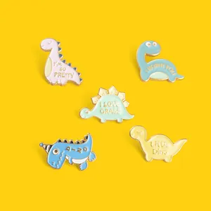 Vue à plat de pins dinosaures colorés en émail sur un fond jaune vif
