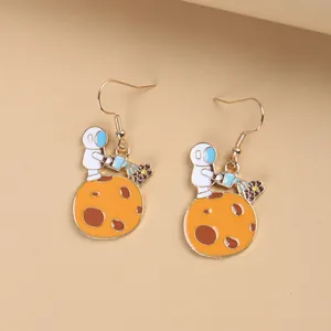 Macro view of cartoon astronaut earrings with enamel star and flower details