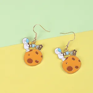 Detail of creative astronaut earrings featuring a spaceman watering a small flower on a planet