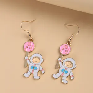 Detail showing cartoon astronaut gold earrings with pink planet enamel and hook design