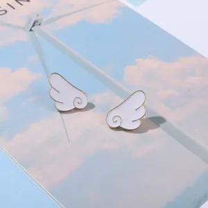Cute cartoon angel wing stud earrings with white enamel finish and golden metal borders