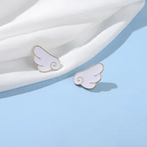 Cartoon white enamel angel wings studs with gold alloy edges on silky background