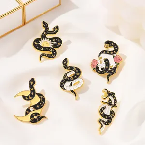 Gothic snake enamel pins set with sun, moon, and skull patterns in black and gold