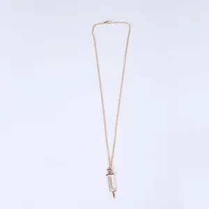Macro detail of a golden syringe pendant necklace for medical students with adjustable chain