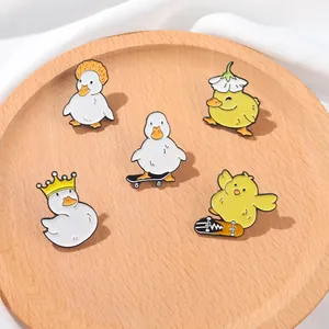Lot de cinq épingles en émail de canards mignons sur un plateau en bois naturel