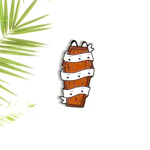 Halloween enamel pin featuring a wood-textured coffin wrapped in ghost bandages