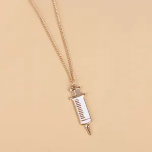 Detailed view of creative golden syringe pendant necklace with white enamel medical scale