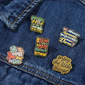 Detail of five retro enamel quote brooches pinned on a blue denim jacket pocket