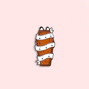 Detail of Halloween coffin enamel pin with white bandages and spooky ghost face patterns
