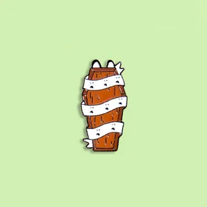 Detail of Halloween enamel brooch showing a brown coffin with ghost bandages and cat ears