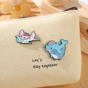 Détail de pins émaillés raie et dauphin mignons sur un sac en toile beige doux