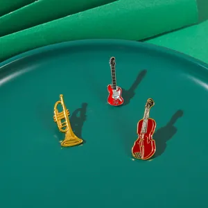 Dettaglio delle spille vintage a forma di strumenti musicali in smalto oro e rosso