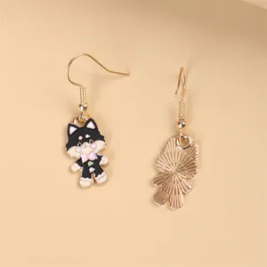 Orecchini asimmetrici a forma di gatto cartoon con fiocco rosa su sfondo beige