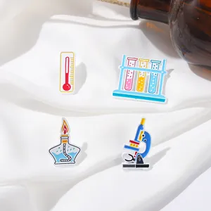 Detail of colorful science pins with microscope and test tubes on white fabric