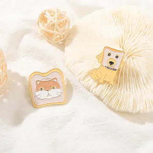 Détail de pins en émail mignons représentant un chat et un chien en toast sur tissu blanc