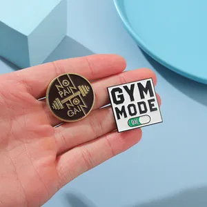Detail of Gym Mode and No Pain No Gain enamel pin badges held in hand for scale