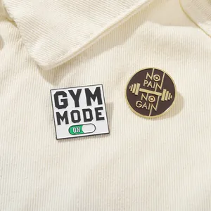 Macro shot of GYM MODE and NO PAIN NO GAIN enamel pins on textured corduroy background