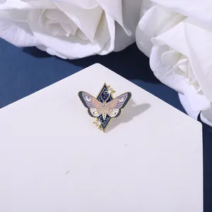 Artistic moth enamel pin featuring moon and stars on a white display block with roses