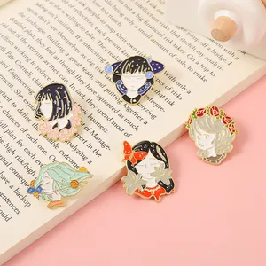 Detalle de cinco pines de esmalte con ilustraciones de chicas anime sobre un libro