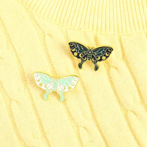 Artistic moth enamel pins with moon phases on a yellow knitted sweater background