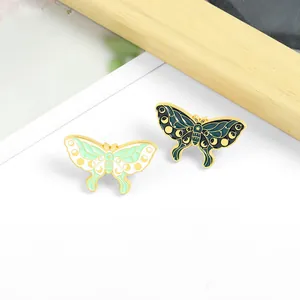 Detailed macro of Van Gogh inspired butterfly enamel pins with moon and star patterns
