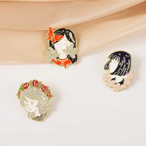 Detalle de tres pines de esmalte con motivos de chicas sobre seda color champán